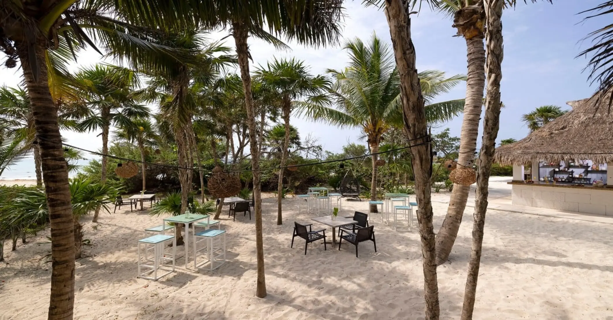 Outdoor seating area at Cocos Bar under palm trees at Paradisus Playa Del Carmen