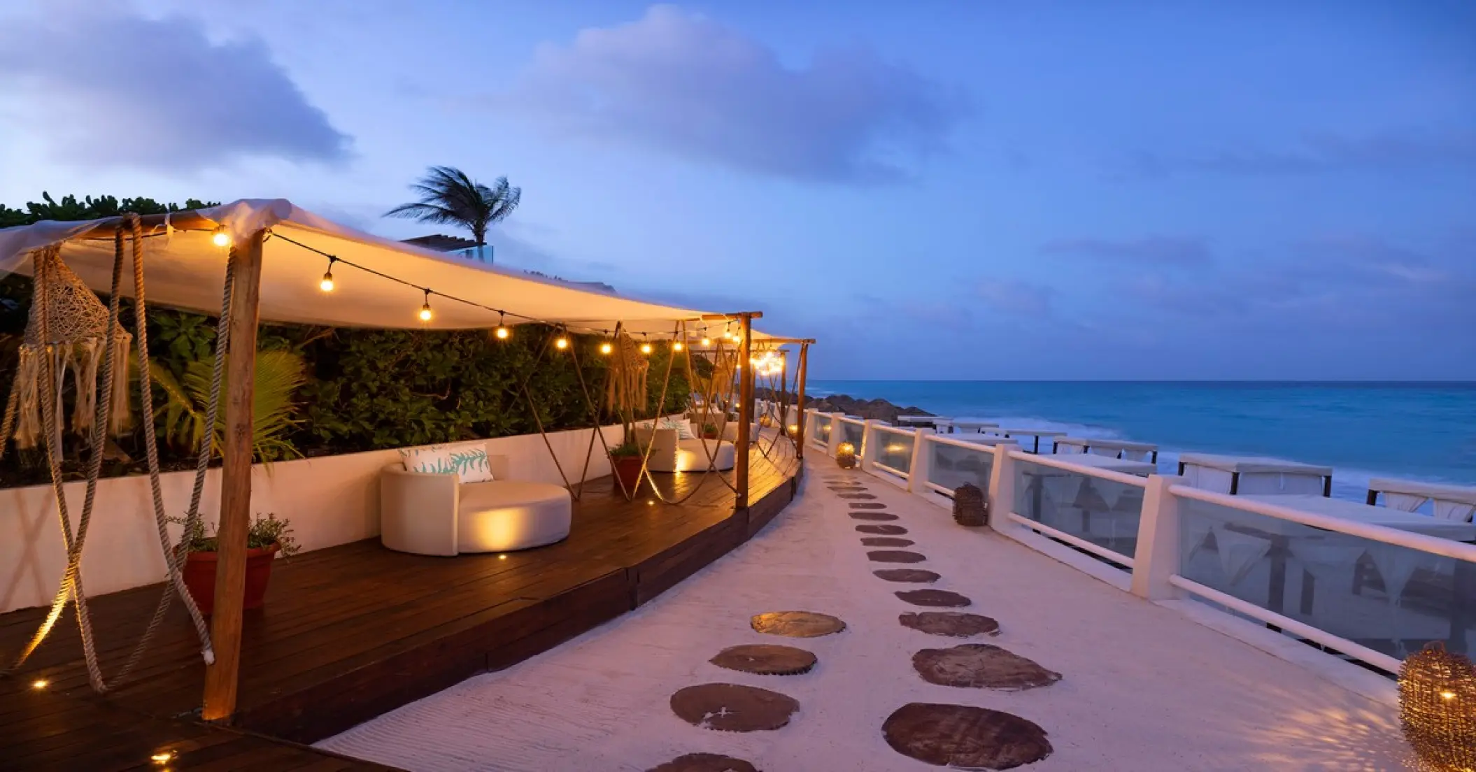 Kanna Beach Club lounge area with string lights and ocean views at Paradisus Cancun, Cancun