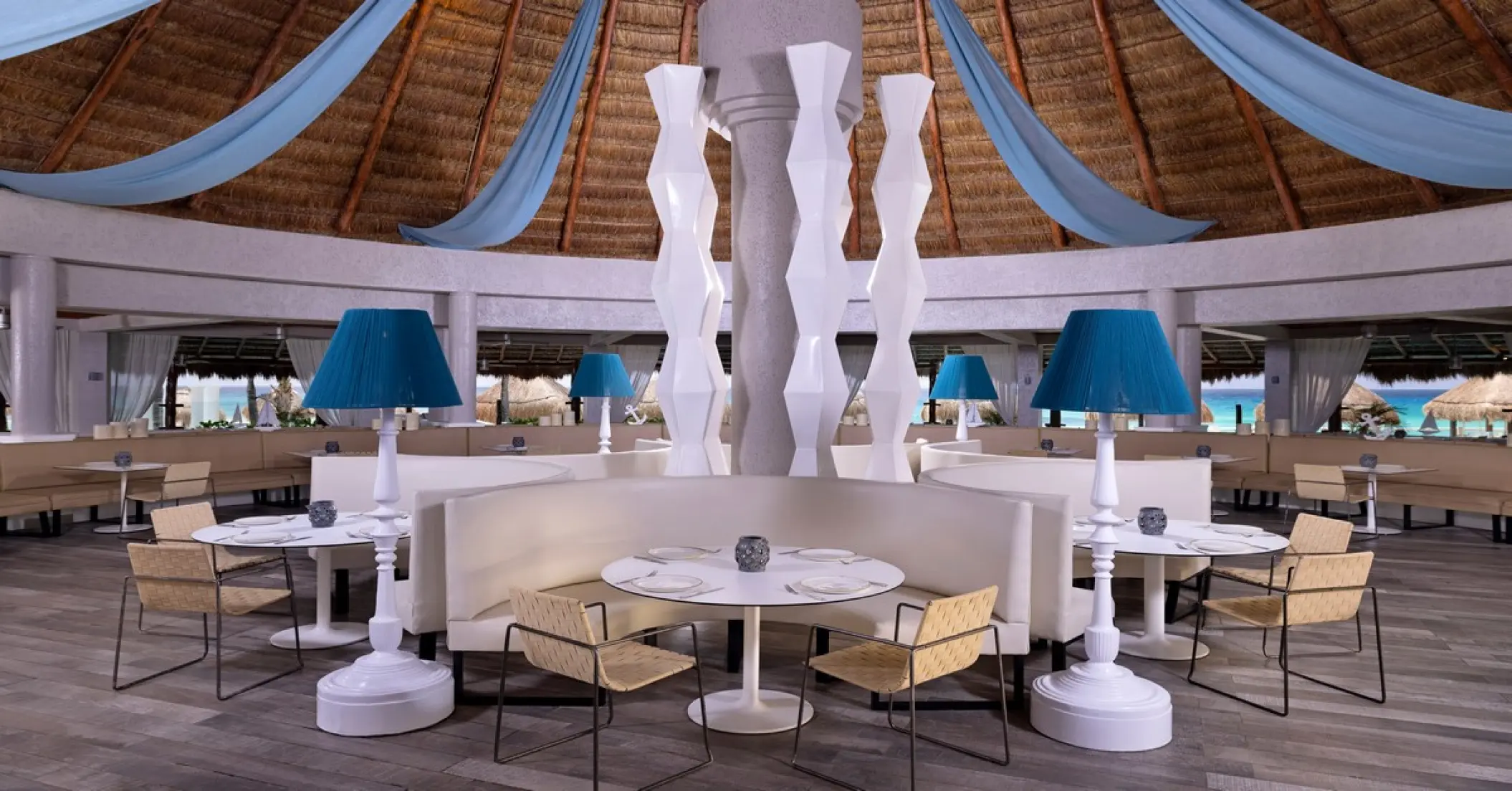 Agua Marina restaurant seating with blue lamps and thatched roof at Paradisus Cancun