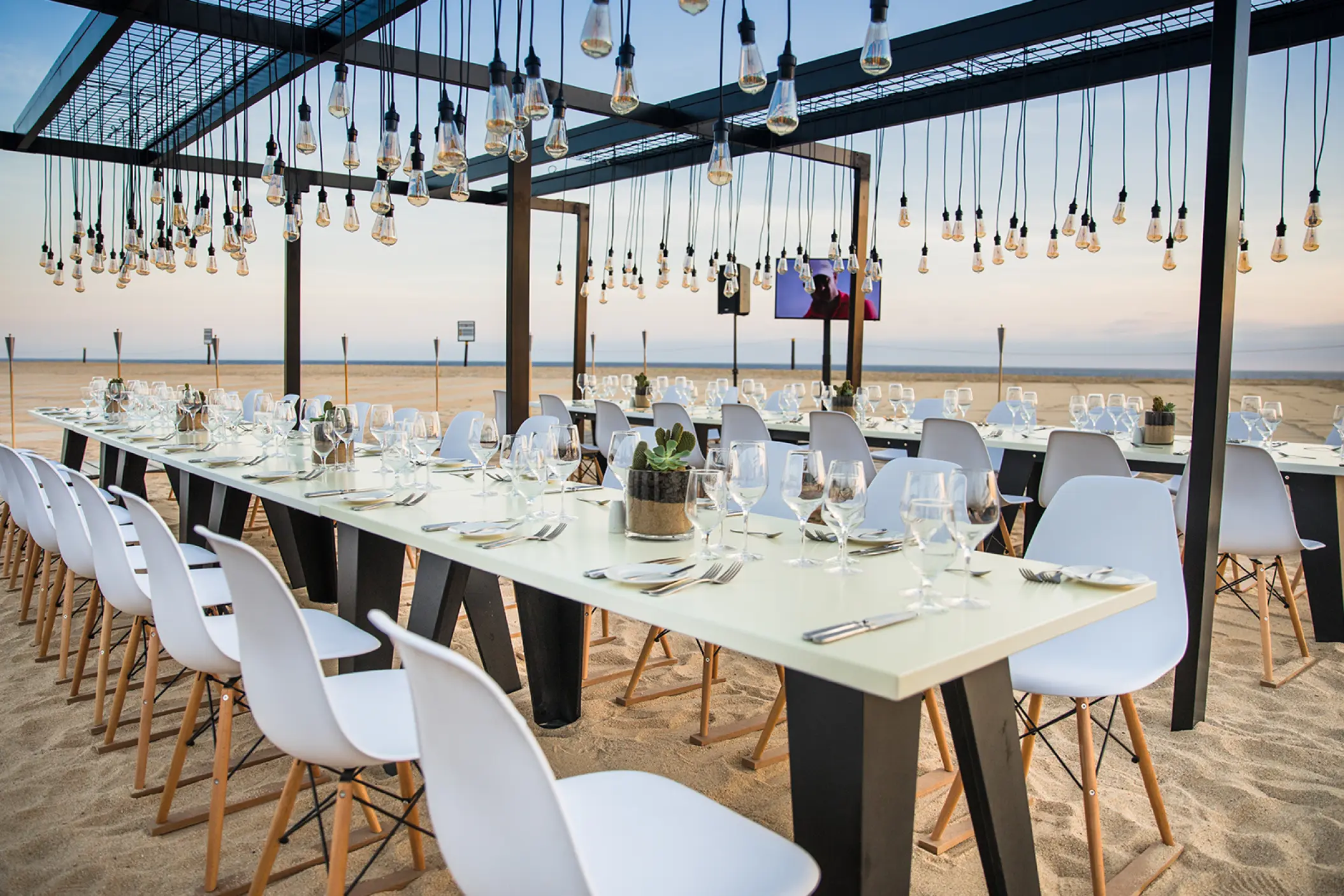 Beachfront wedding reception setup under hanging Edison bulbs at Pueblo Bonito Pacifica, Cabo San Lucas
