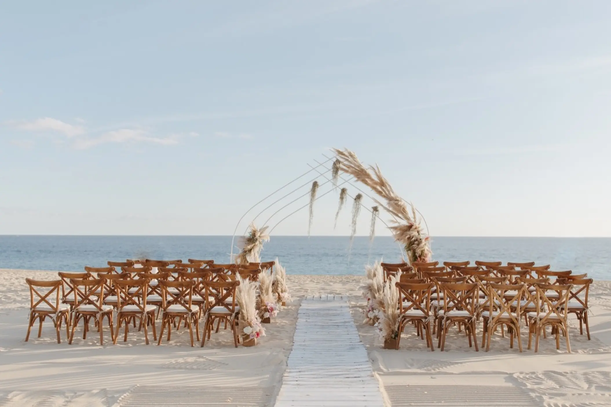 Beach wedding ceremony setup with pampas grass arch at Pueblo Bonito Pacifica, Cabo San Lucas