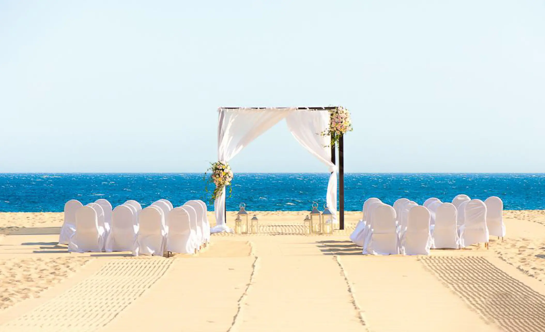 Beachfront wedding ceremony with white draped arch at Pueblo Bonito Pacifica, Cabo San Lucas