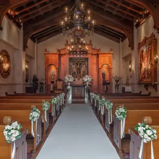 Chapel wedding ceremony venue with wooden pews and floral aisle decor at Pueblo Bonito Sunset Beach, Cabo San Lucas