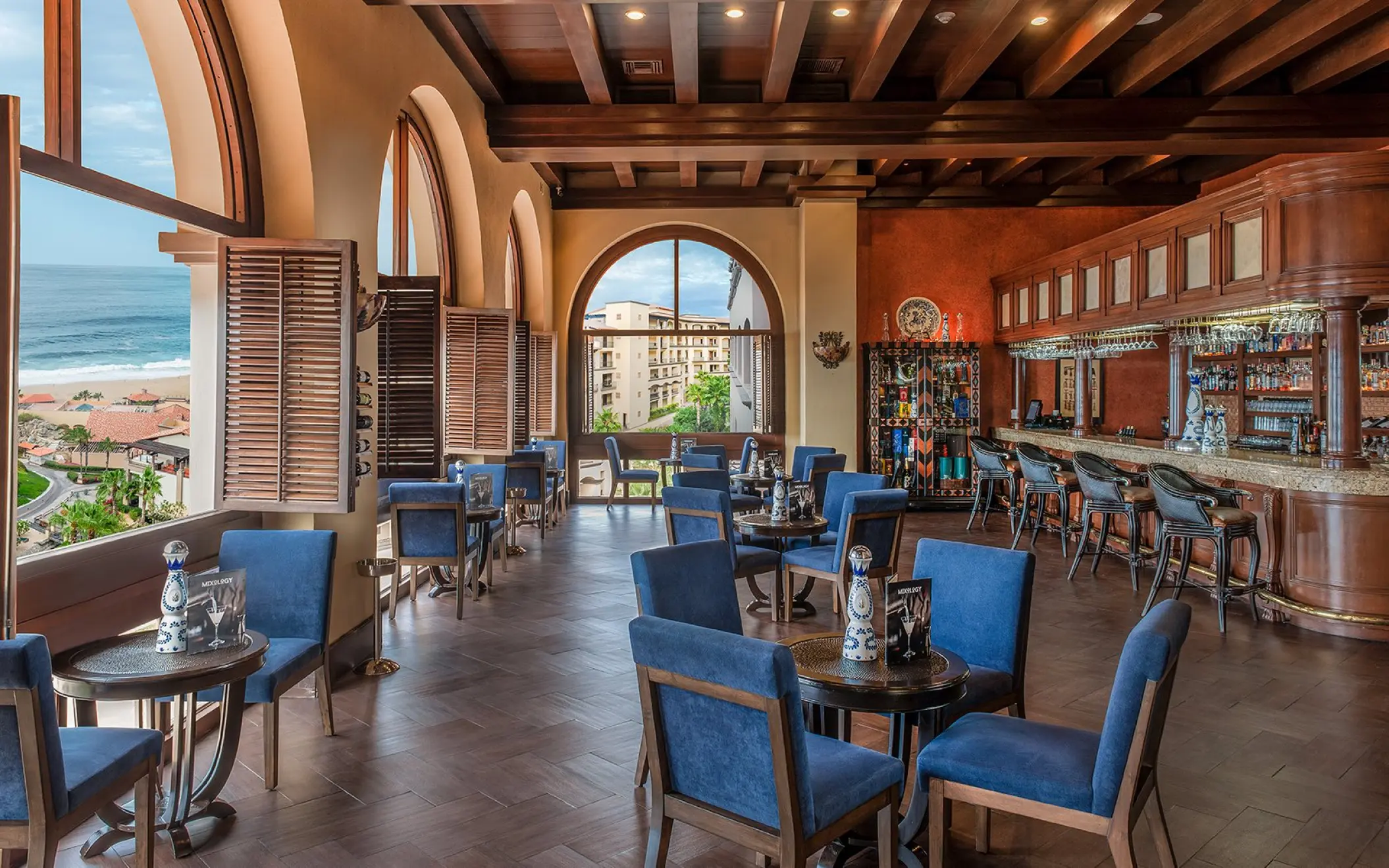 Indoor lobby bar with blue seating and arched windows at Pueblo Bonito Sunset Beach, Cabo San Lucas