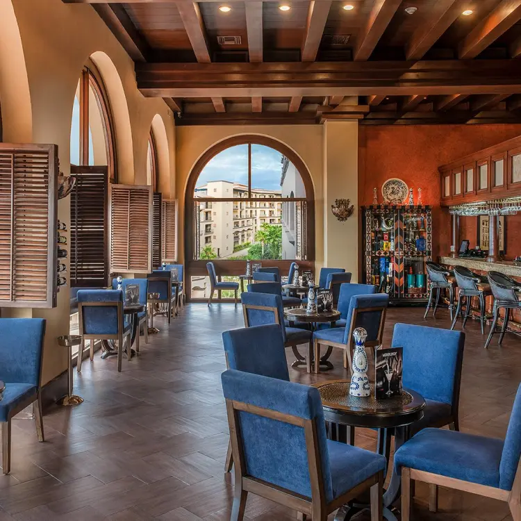 Indoor lobby bar with blue seating and arched windows at Pueblo Bonito Sunset Beach, Cabo San Lucas