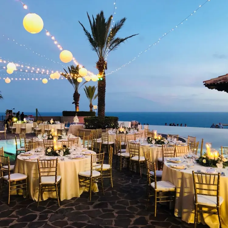 Outdoor wedding reception with string lights and round tables at Pueblo Bonito Sunset Beach, Cabo San Lucas