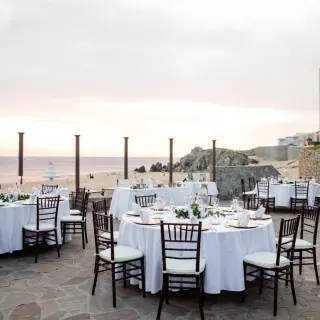 Terrace wedding reception with white table linens and brown chairs at Pueblo Bonito Sunset Beach, Cabo San Lucas