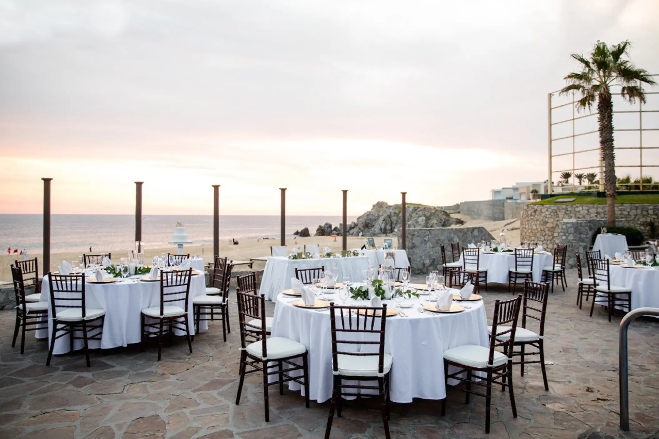 Terrace wedding reception with white table linens and brown chairs at Pueblo Bonito Sunset Beach, Cabo San Lucas