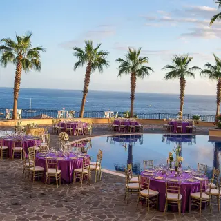 Poolside wedding reception with purple linens and palm trees at Pueblo Bonito Sunset Beach, Cabo San Lucas