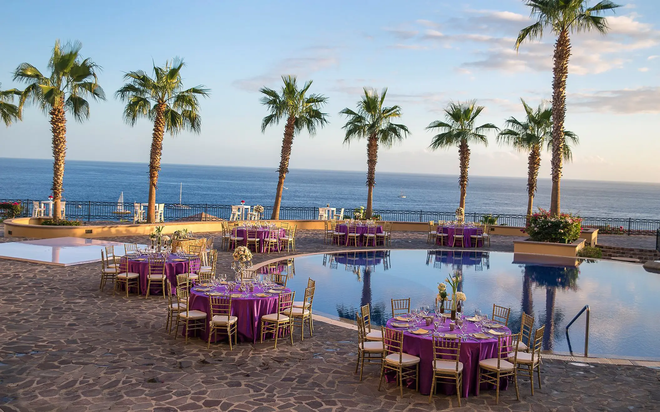 Poolside wedding reception with purple linens and palm trees at Pueblo Bonito Sunset Beach, Cabo San Lucas