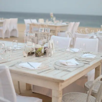 Beachfront wedding reception setup with white wooden tables at Pueblo Bonito Sunset Beach, Cabo San Lucas