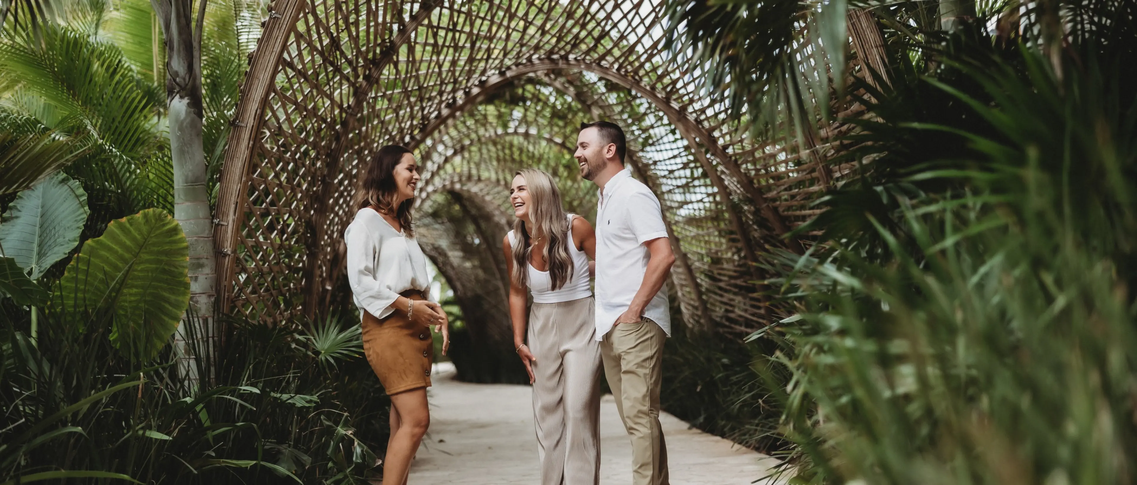Paradise Weddings planner chatting with a couple under a bamboo tunnel at Secrets Playa Mujeres