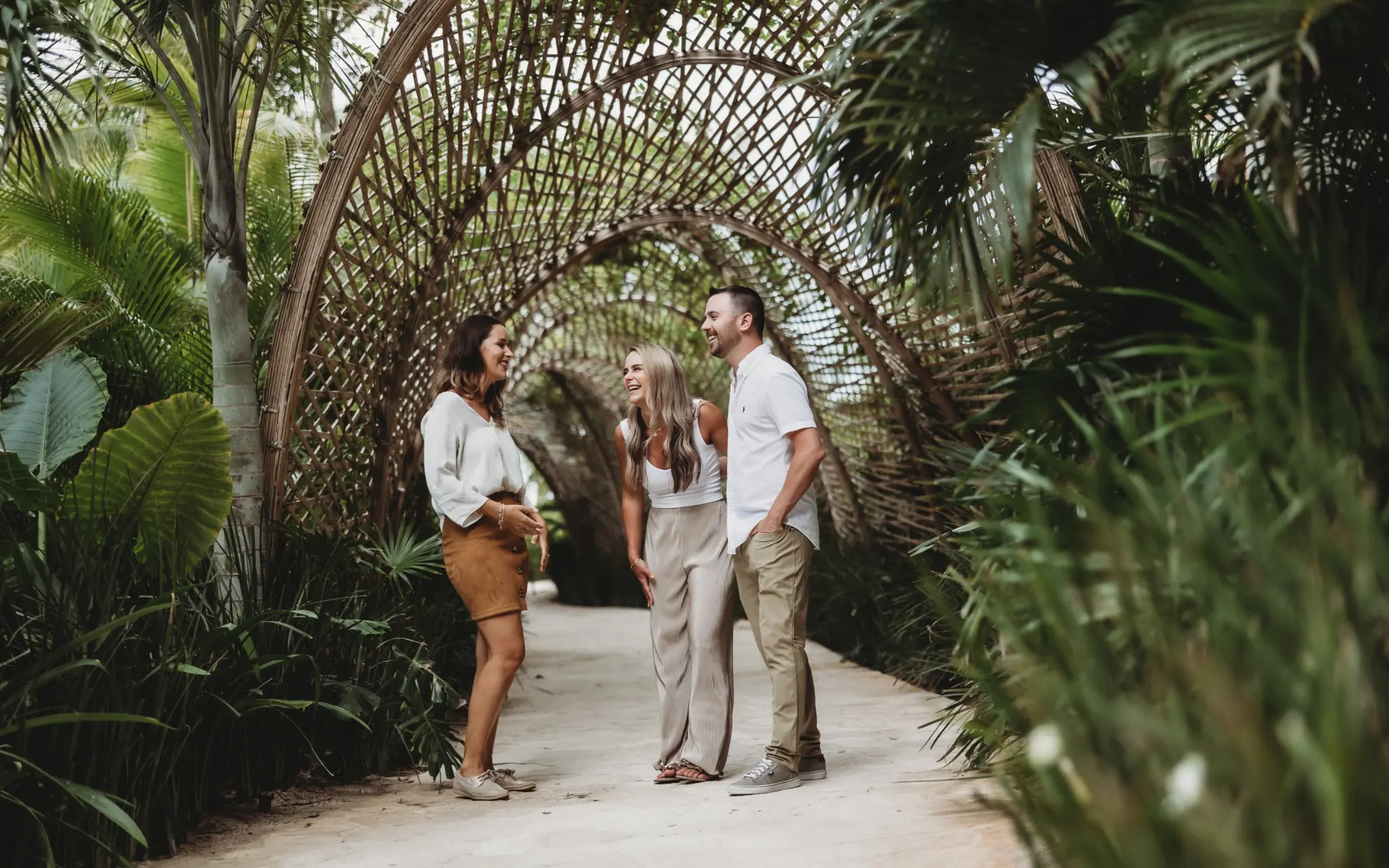 Paradise Weddings planner chatting with a couple under a bamboo tunnel at Secrets Playa Mujeres