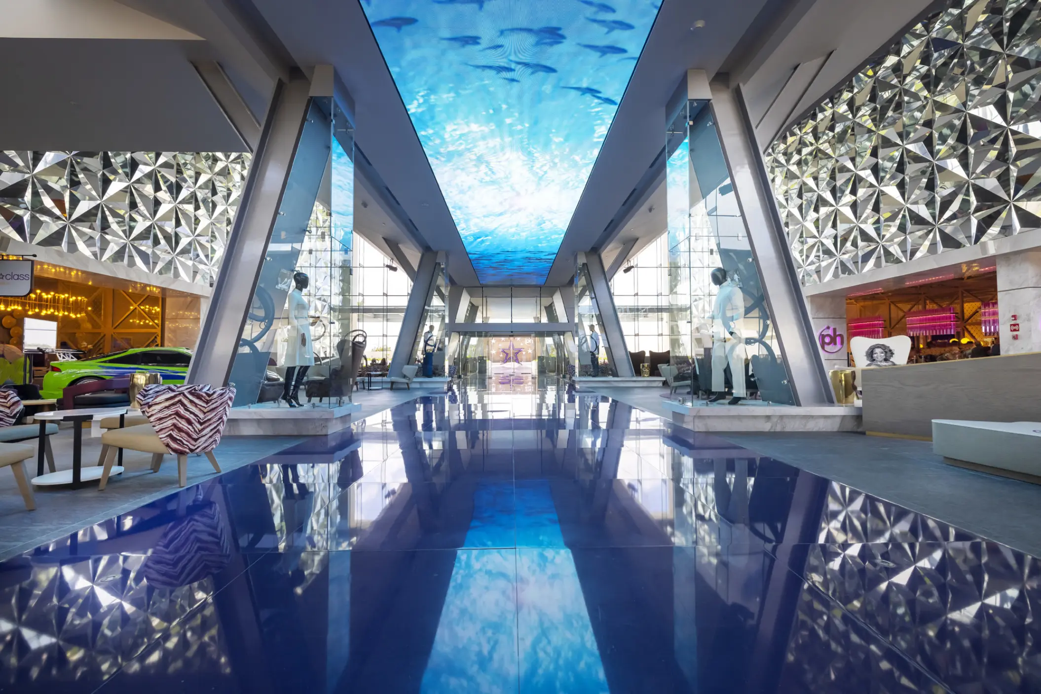 Modern lobby with blue reflective floors and aquatic ceiling screen at Planet Hollywood Adult Scene, Cancun
