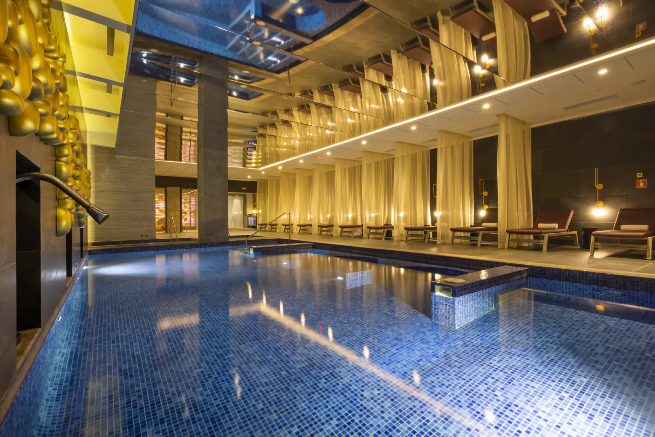 Indoor spa pool with lounge chairs and draped curtains at Planet Hollywood Adult Scene, Cancun