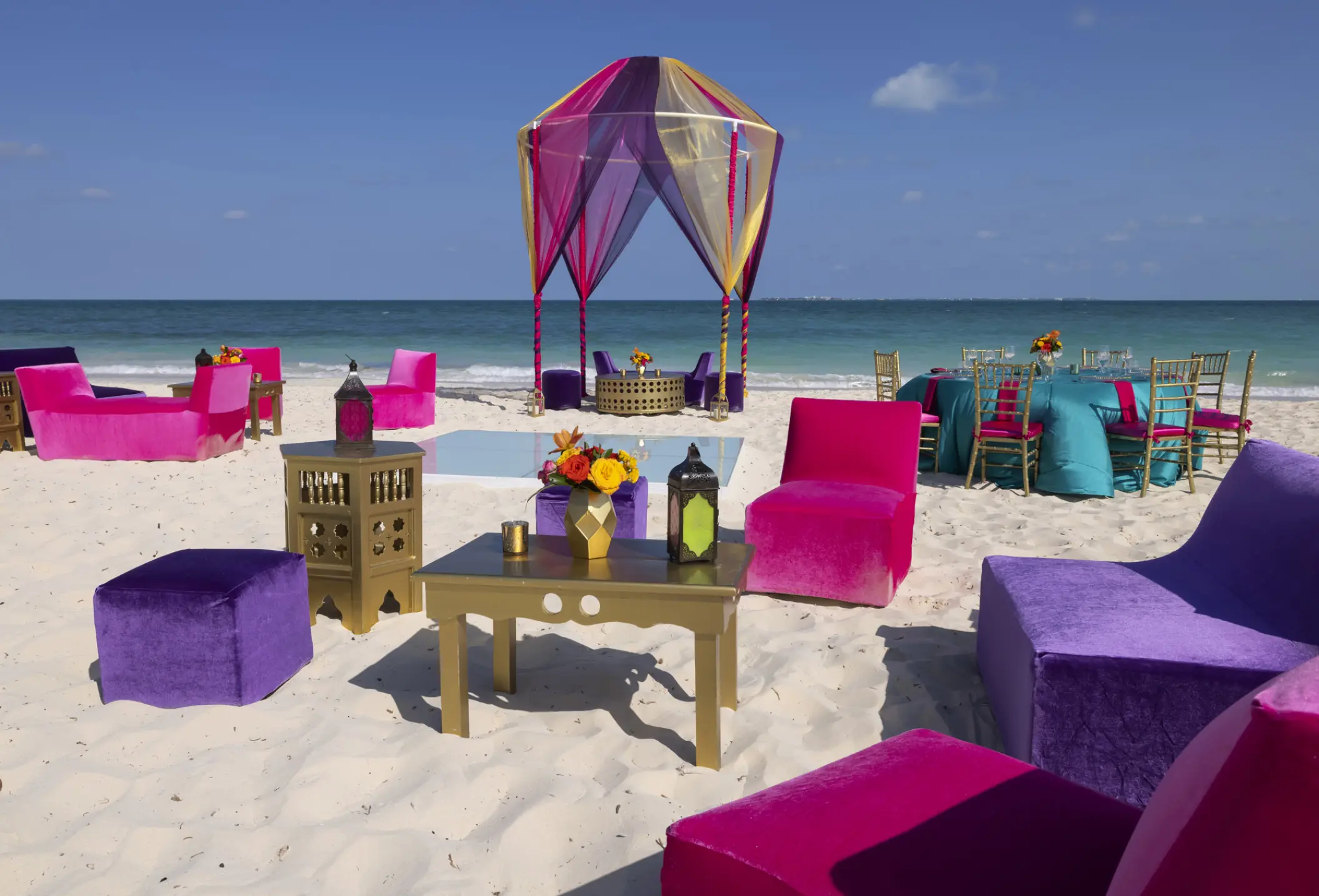 Colorful beach wedding reception setup with vibrant pink and purple lounge seating at Planet Hollywood Cancun