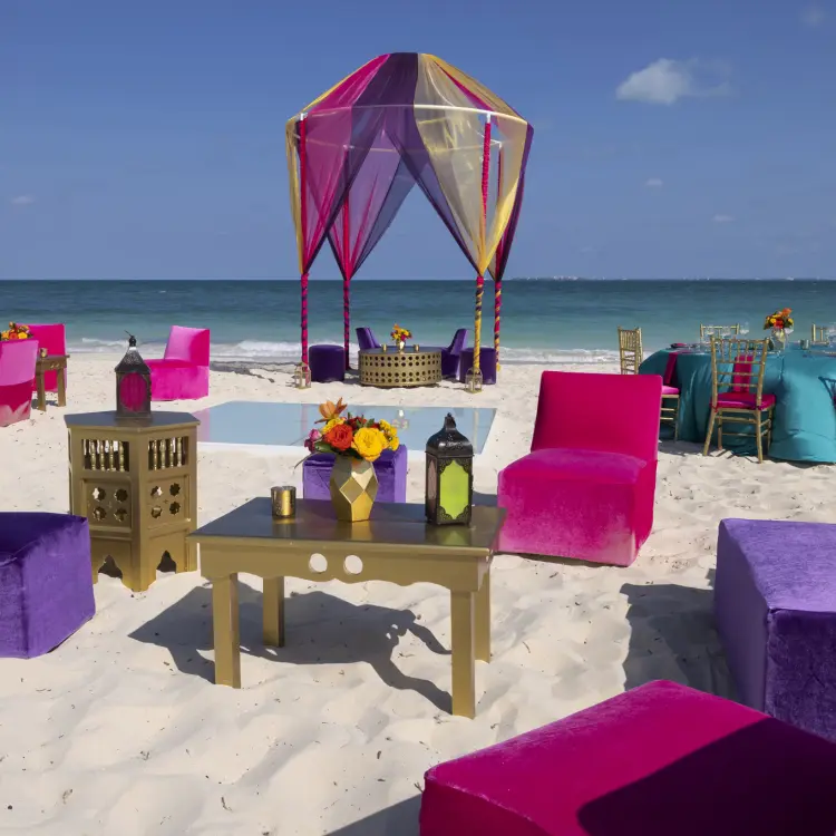 Colorful beach wedding reception setup with vibrant pink and purple lounge seating at Planet Hollywood Cancun