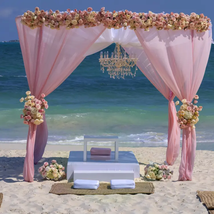 Beachfront wedding ceremony arch with pink draping and a chandelier at Planet Hollywood Cancun