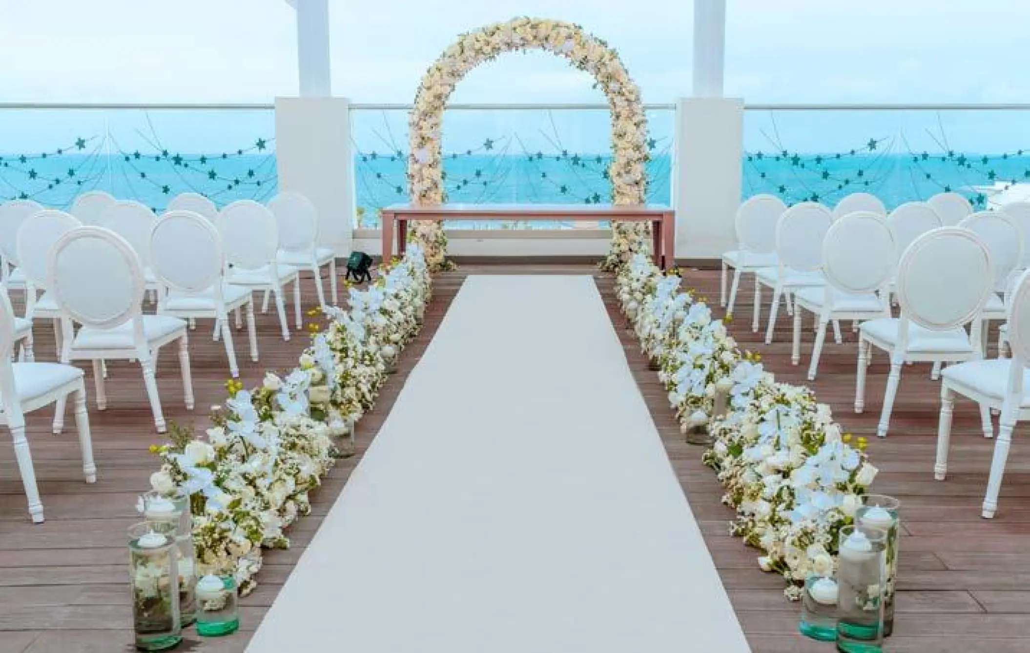 Rooftop wedding ceremony setup with white floral arch and ocean views at Planet Hollywood Cancun