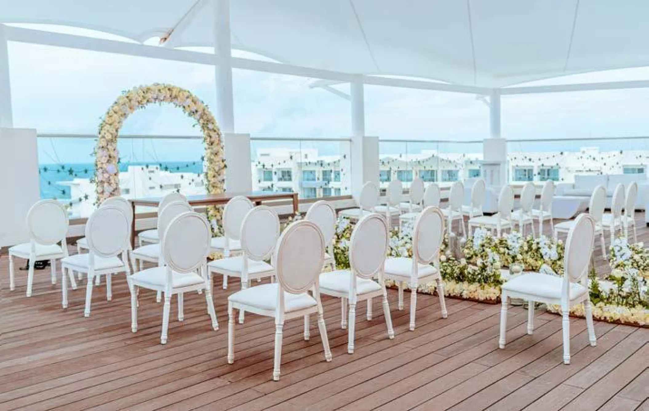 Rooftop wedding ceremony with white chairs and a floral arch at Planet Hollywood Cancun