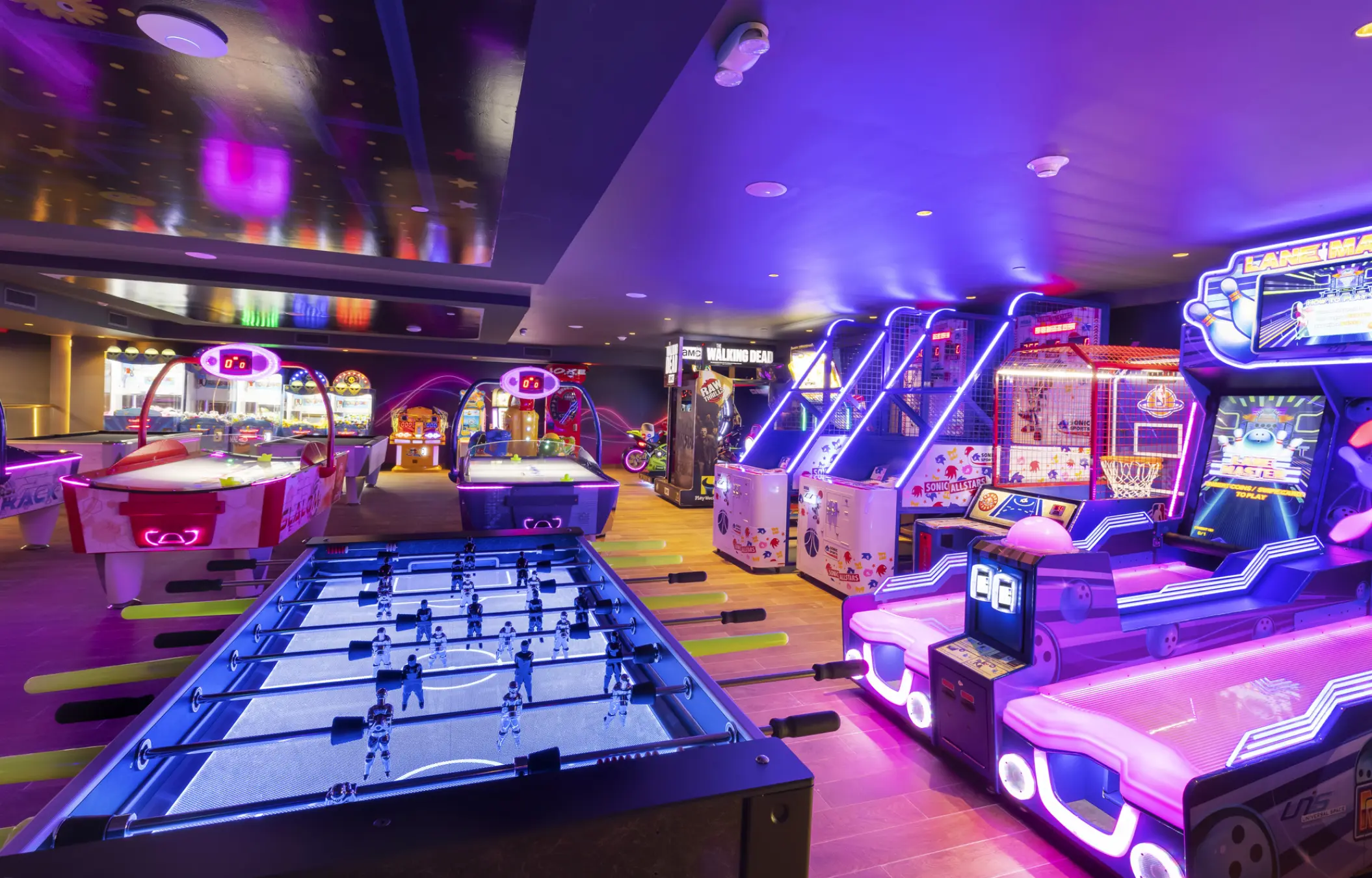 Arcade games, foosball and air hockey tables under neon lights at Planet Hollywood Cancun