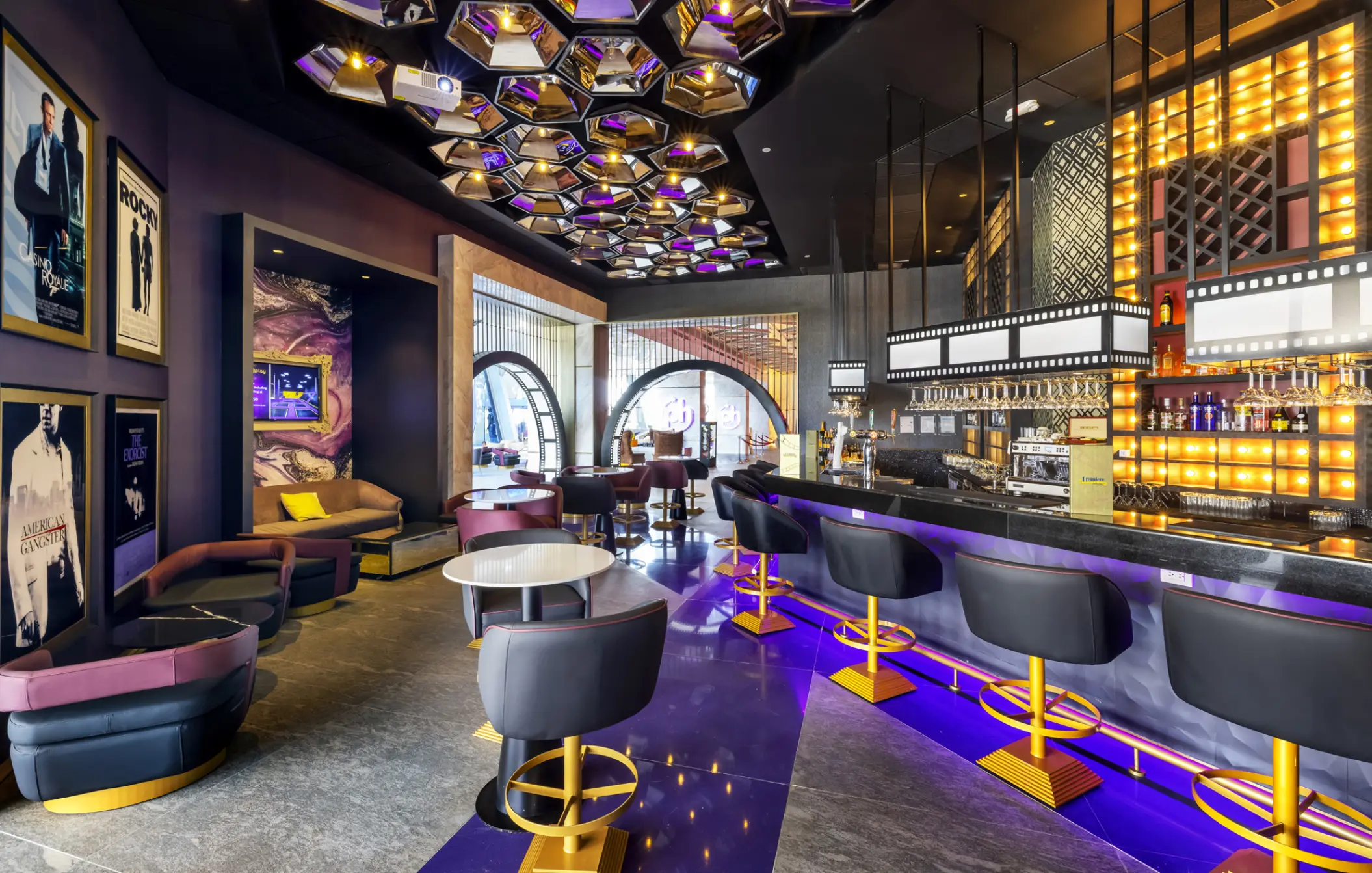 The Premier Bar at Planet Hollywood Cancun featuring movie posters, purple accents, and a film-reel light fixture