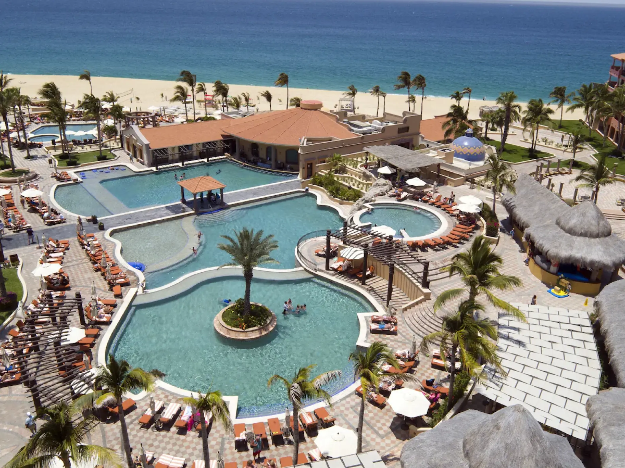 Aerial view of multi-tiered swimming pools and palm trees at Playa Grande Resort, Cabo San Lucas