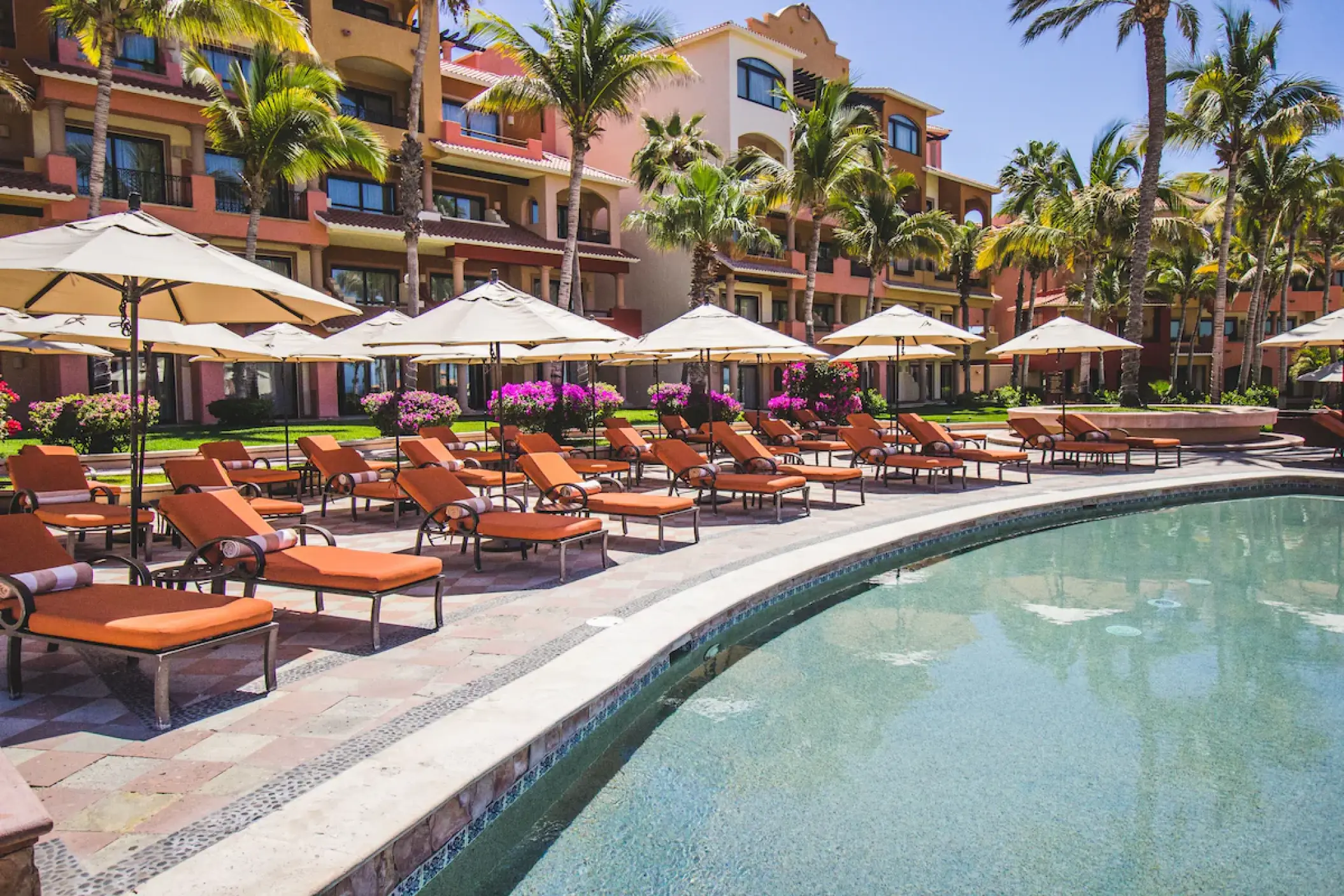 Playa Grande Resort outdoor pool with orange lounge chairs and umbrellas, Cabo San Lucas