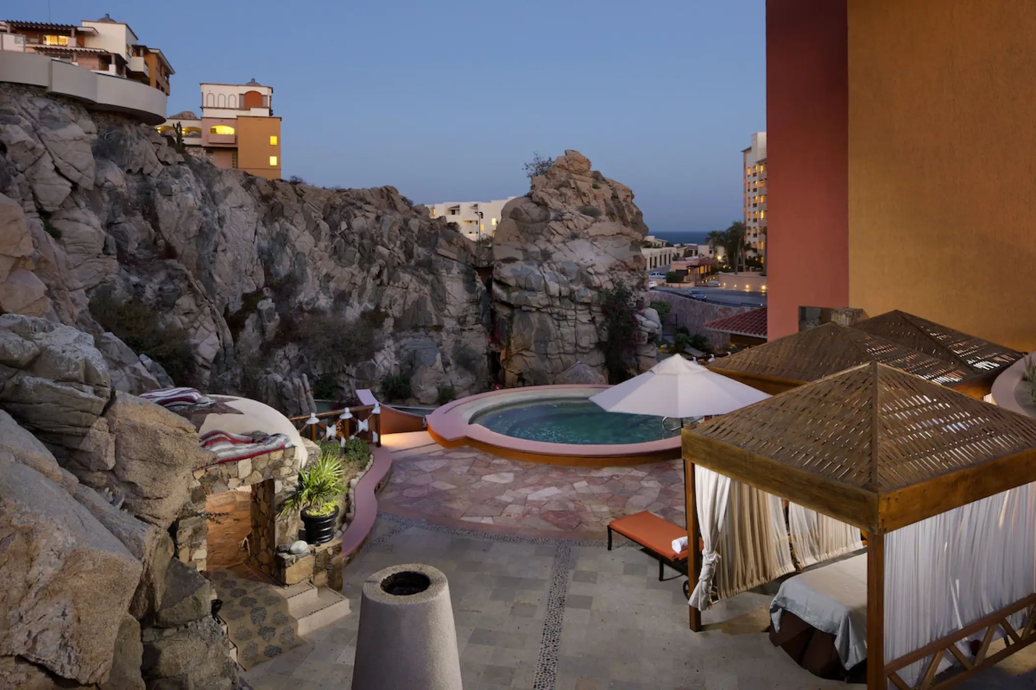 Playa Grande Resort outdoor spa with a circular pool and massage cabanas among cliffs in Cabo San Lucas