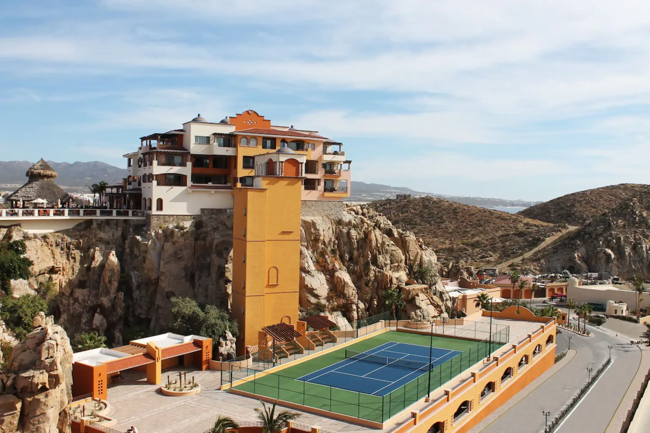 Outdoor tennis court and cliffside buildings at Playa Grande Resort, Cabo San Lucas