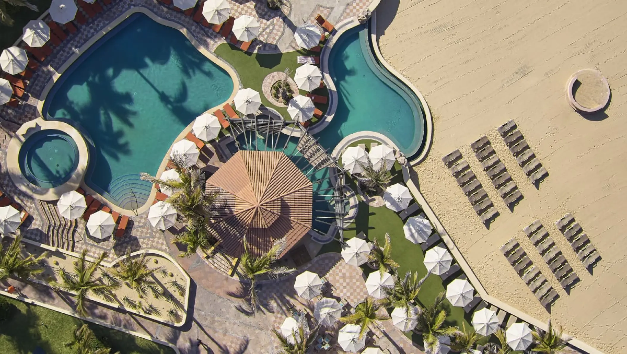 Aerial view of swimming pools and beachfront sun loungers at Playa Grande Resort, Cabo San Lucas