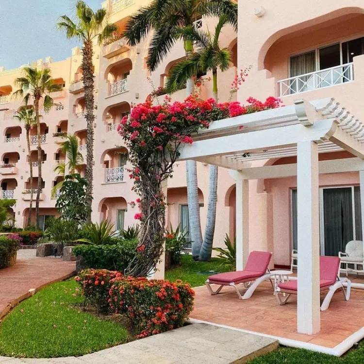 White pergola and pink lounge chairs in the garden at Pueblo Bonito Rose, Cabo San Lucas