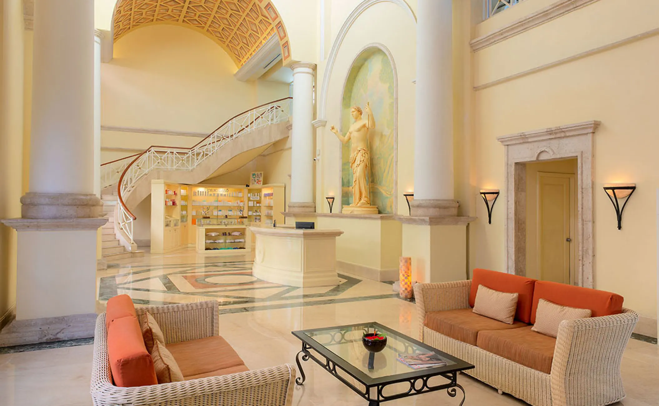Grand lobby with high ceilings, white columns, and a curved staircase at Pueblo Bonito Rose, Cabo San Lucas