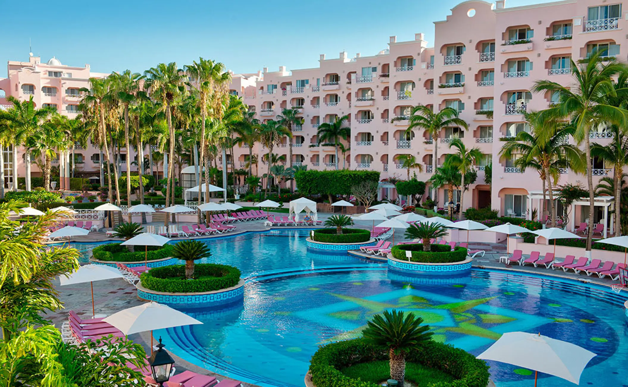 Outdoor pool area and pink guest room buildings at Pueblo Bonito Rose, Cabo San Lucas