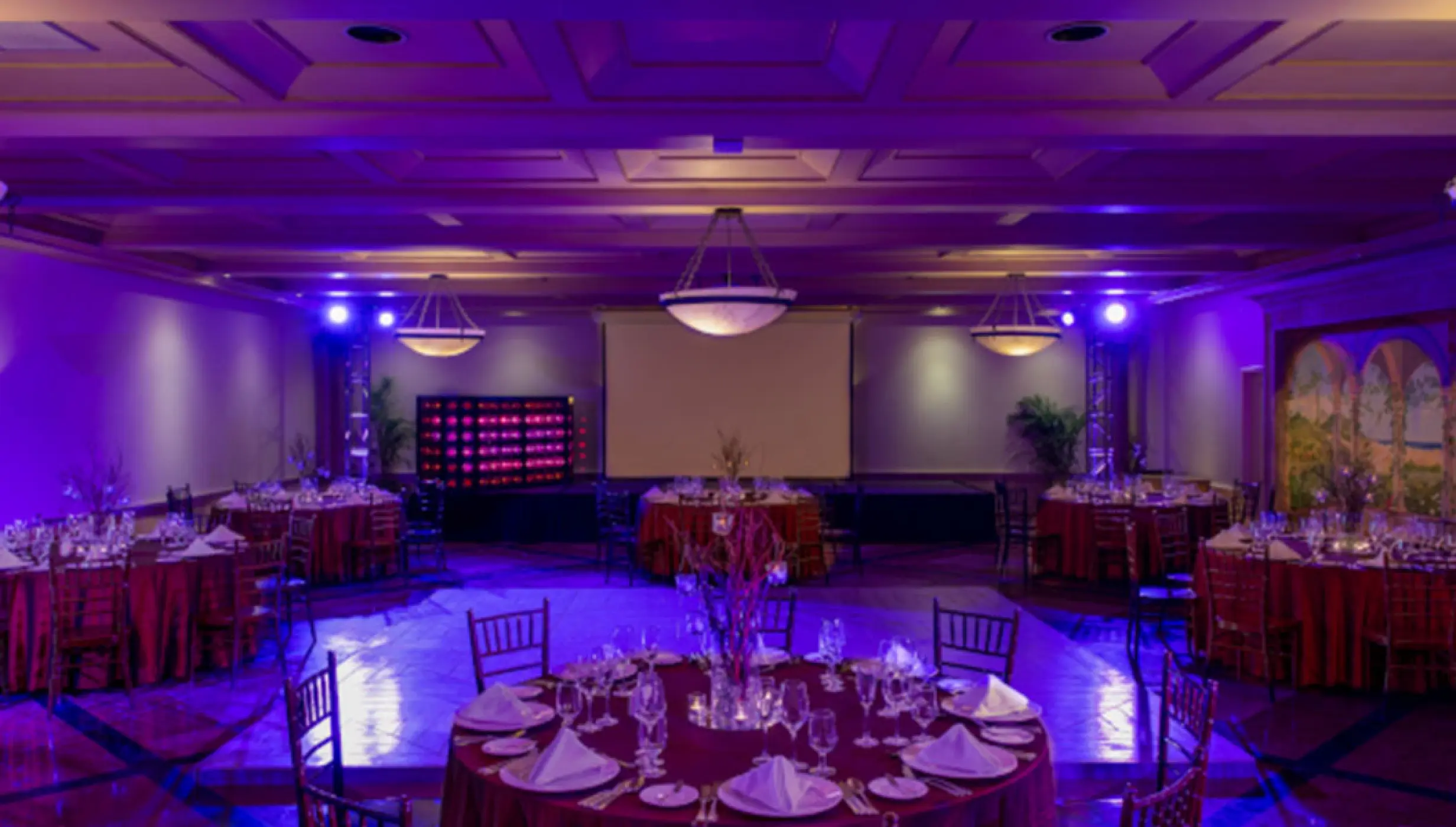 Ballroom wedding reception with purple lighting and round tables at Pueblo Bonito Rose, Cabo San Lucas