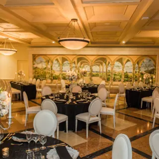 Indoor ballroom wedding reception with black tablecloths and white chairs at Pueblo Bonito Rose, Cabo San Lucas