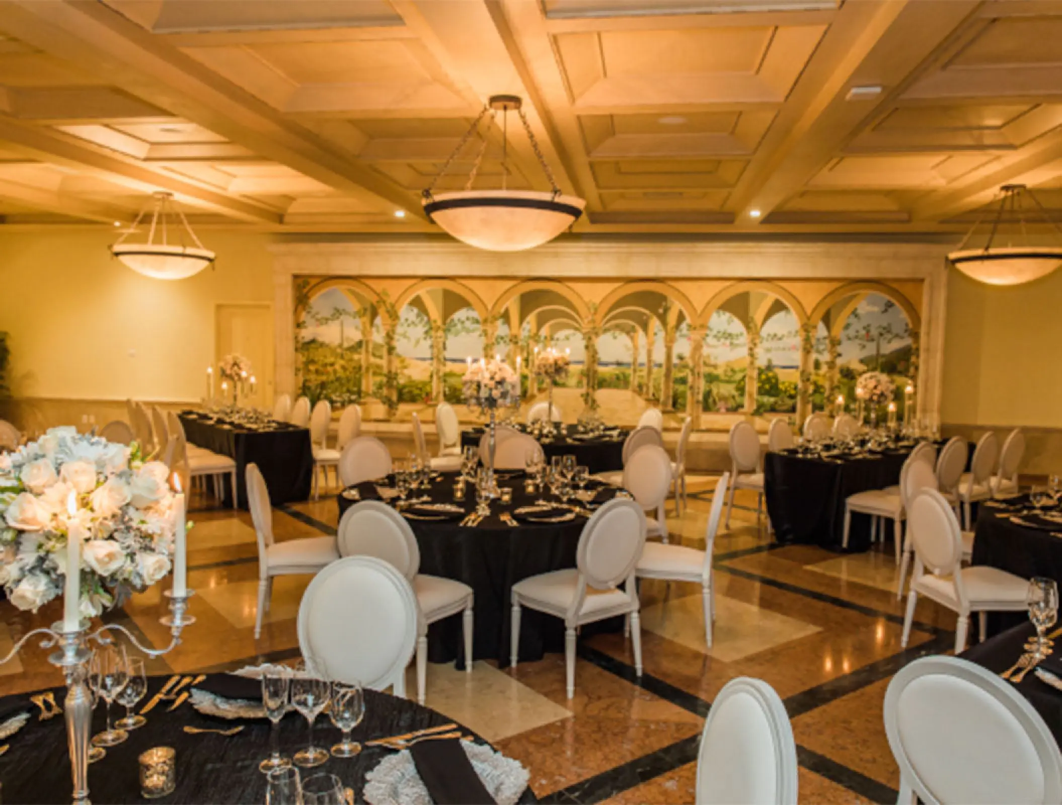 Indoor ballroom wedding reception with black tablecloths and white chairs at Pueblo Bonito Rose, Cabo San Lucas