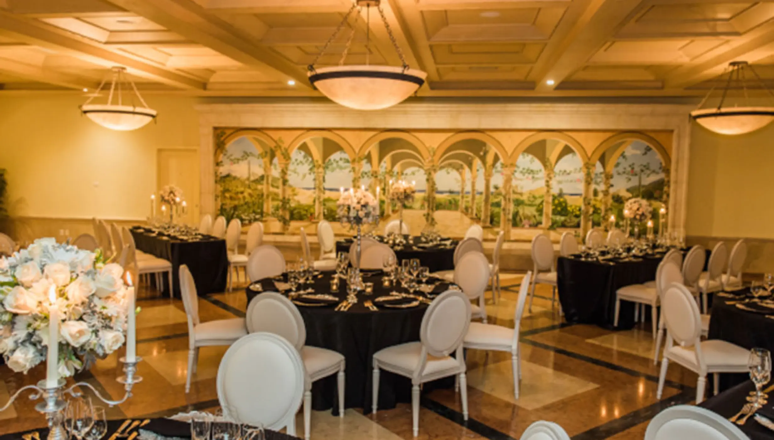 Indoor wedding reception with black linens and white chairs at Pueblo Bonito Rose, Cabo San Lucas