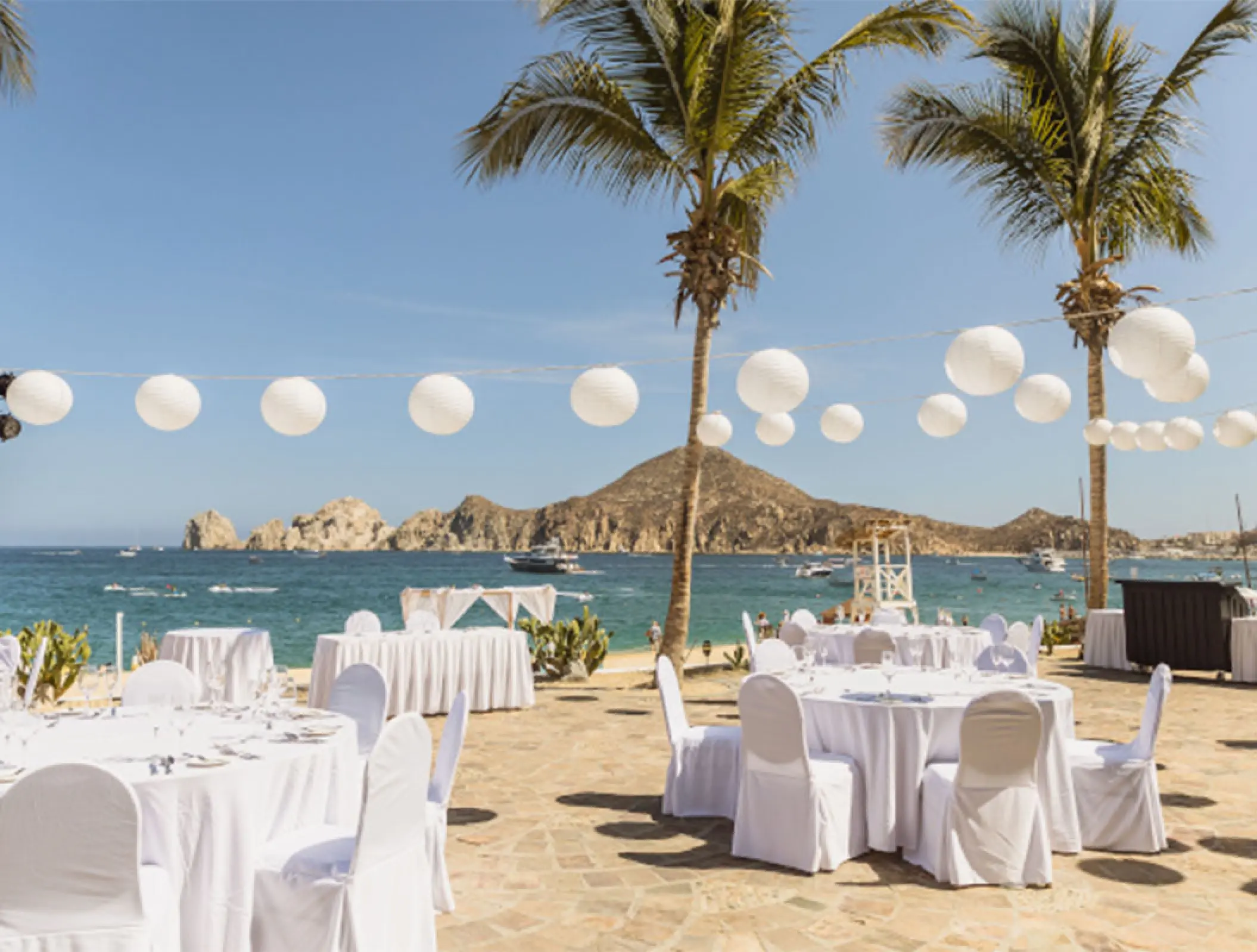 Outdoor wedding reception setup with white lanterns and sea views at Pueblo Bonito Rose, Cabo San Lucas