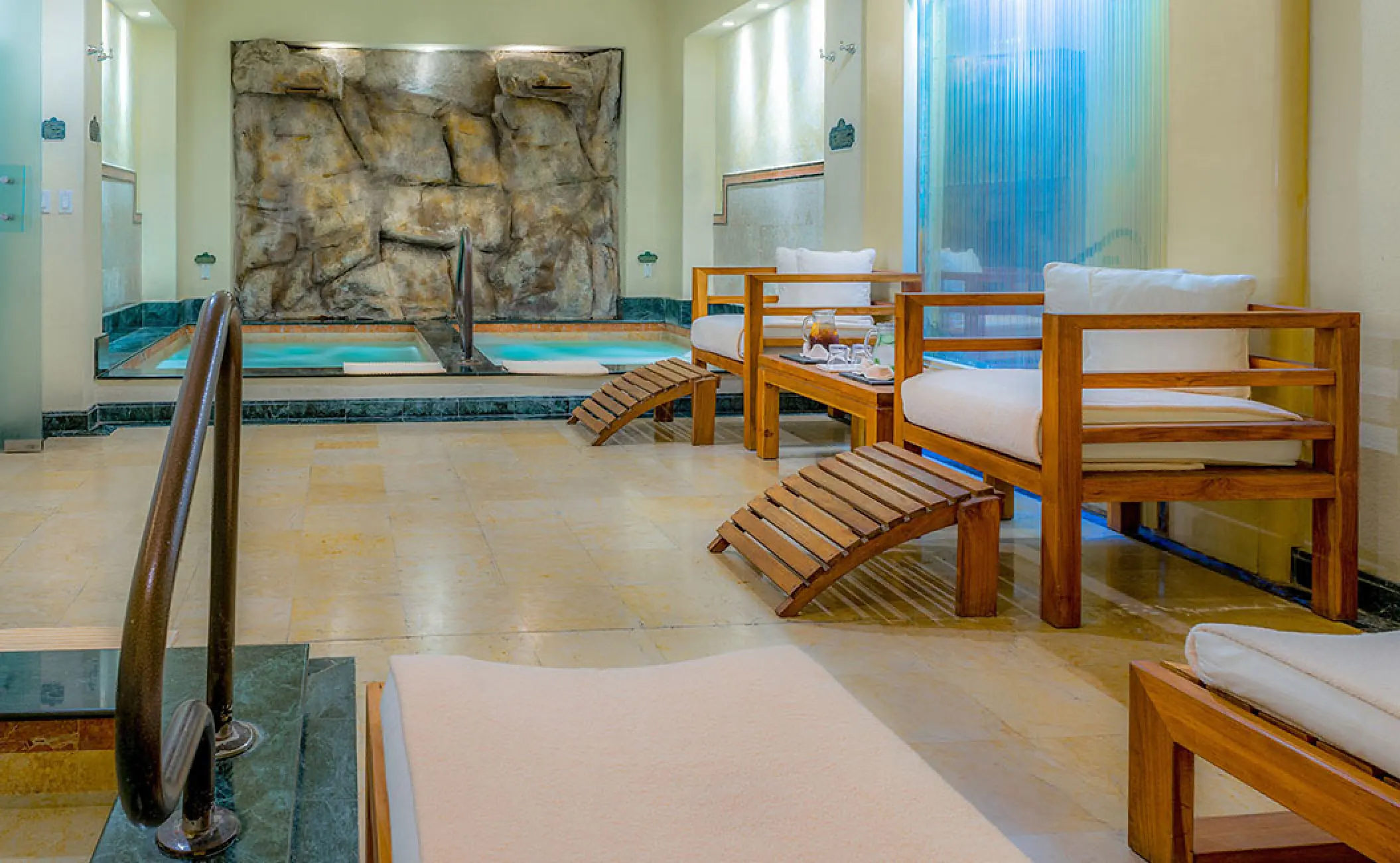 Spa lounge with wooden armchairs and a small hydrotherapy pool at Pueblo Bonito Rose, Cabo San Lucas