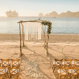 Beachfront wedding ceremony with a macramé arch and cross-back chairs at Pueblo Bonito Rose, Cabo San Lucas