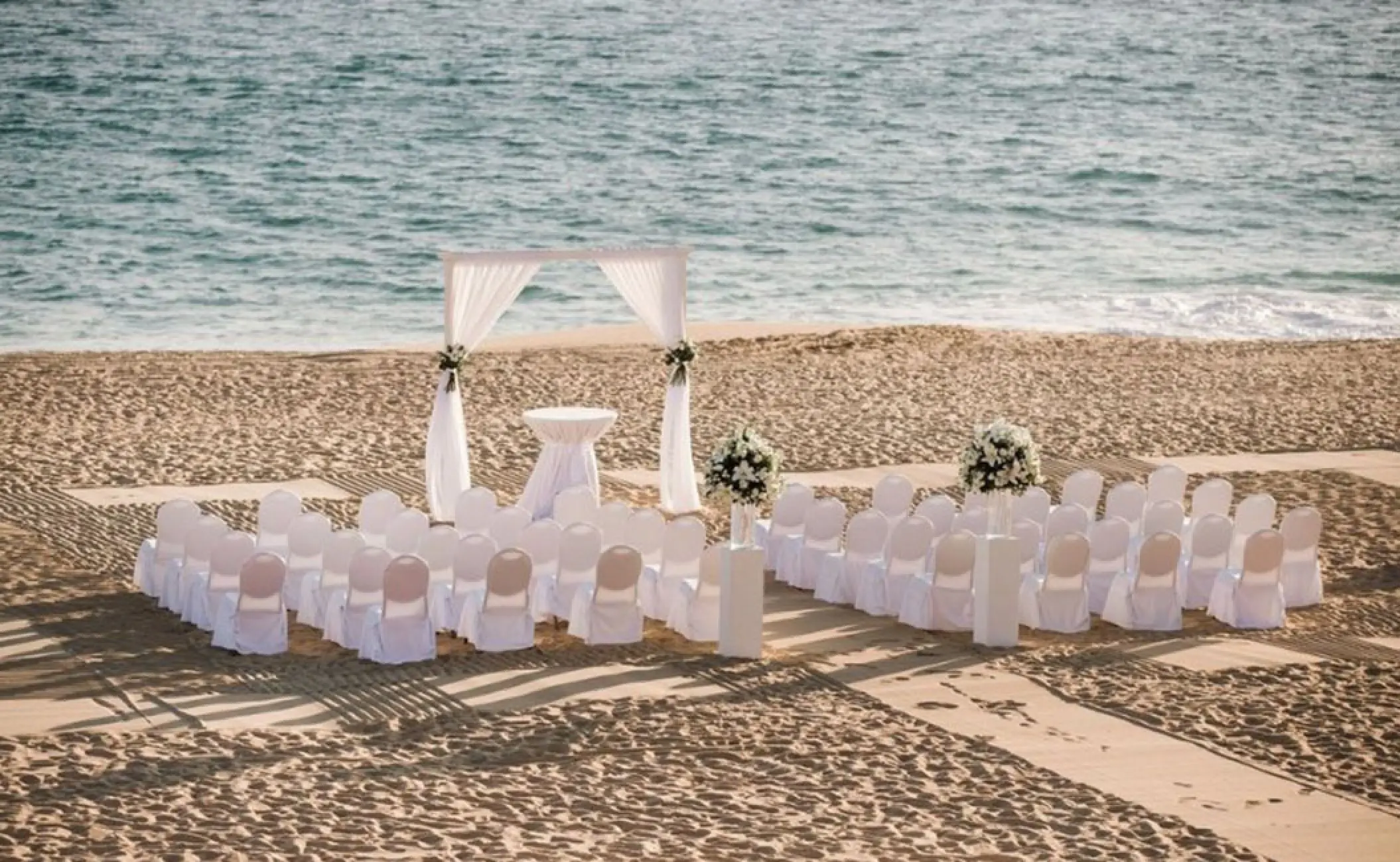 Beachfront wedding ceremony setup with white draped arch at Pueblo Bonito Rose, Cabo San Lucas