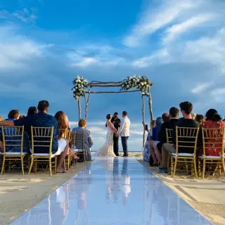 Beachfront wedding ceremony with a white aisle runner and gold chairs at Pueblo Bonito Rose, Cabo San Lucas