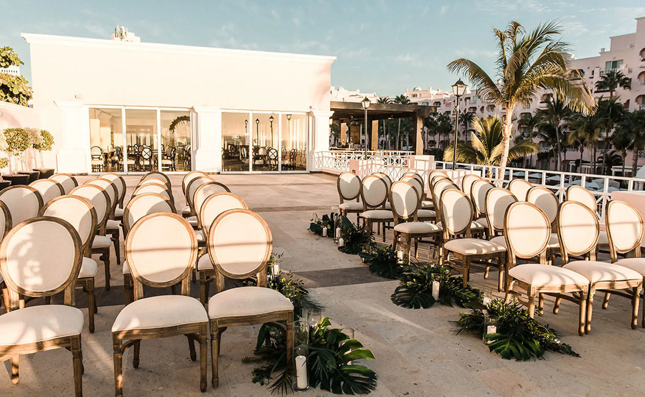 Terrace wedding ceremony setup with wooden chairs and greenery at Pueblo Bonito Rose, Cabo San Lucas