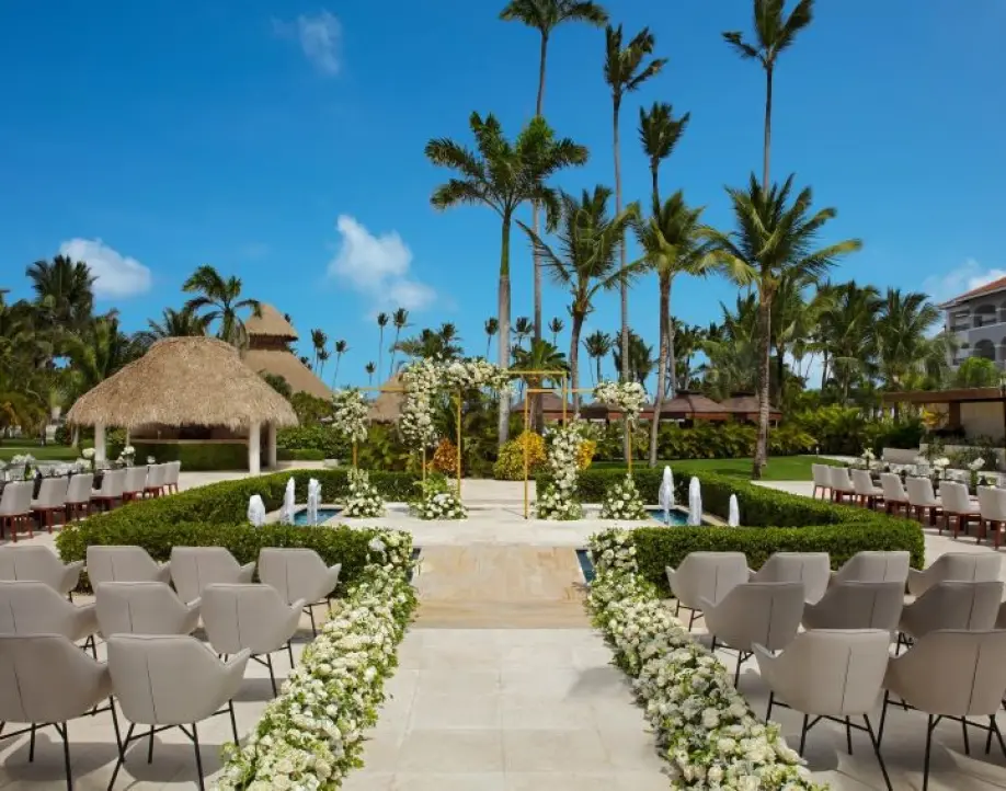 Outdoor wedding ceremony setup with white floral aisle runners and fountains in Punta Cana
