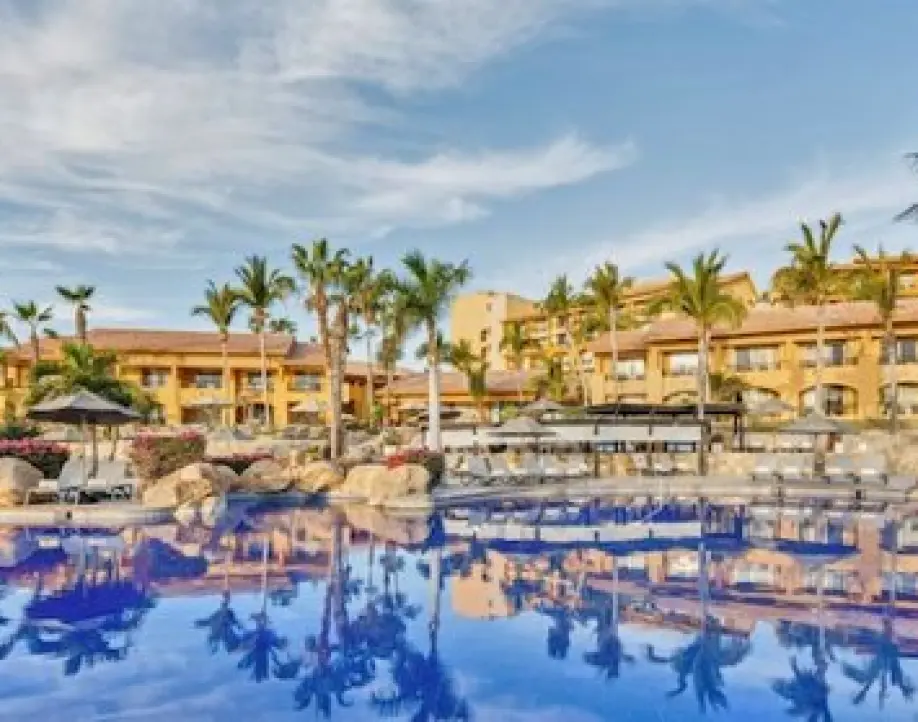 All-inclusive resort pool area with palm trees and sun loungers in Cabo San Lucas