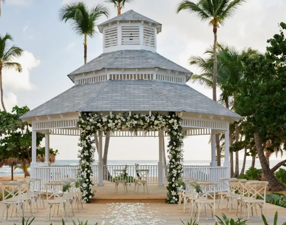 Beachfront gazebo wedding ceremony setup with white flowers and palm trees, Punta Cana