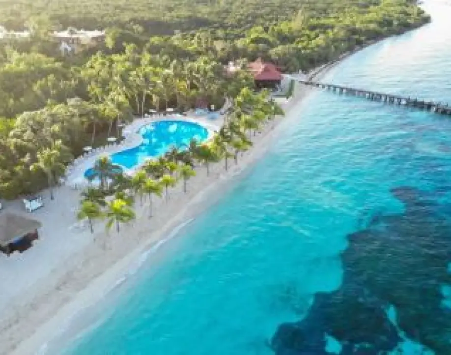 Aerial view of a beachfront pool and wooden pier over turquoise water in Cozumel