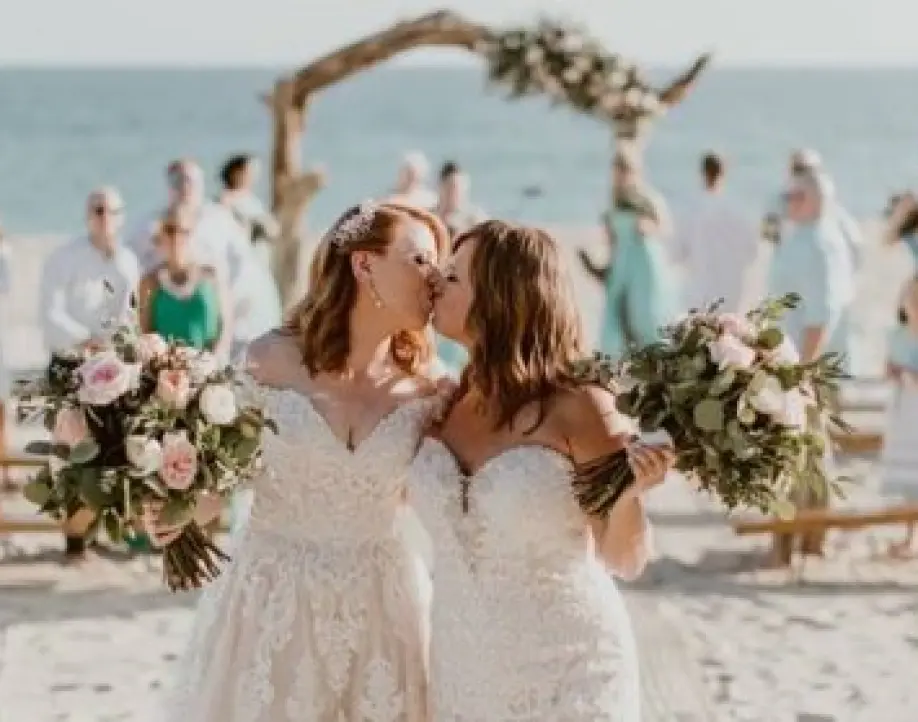 Brides kissing during a beach ceremony at Conrad Punta Mita, Puerto Vallarta