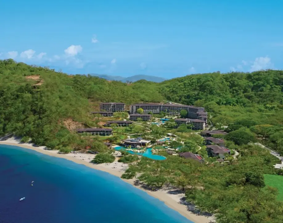 Aerial view of Dreams Las Mareas surrounded by lush green hills and a turquoise bay, Costa Rica